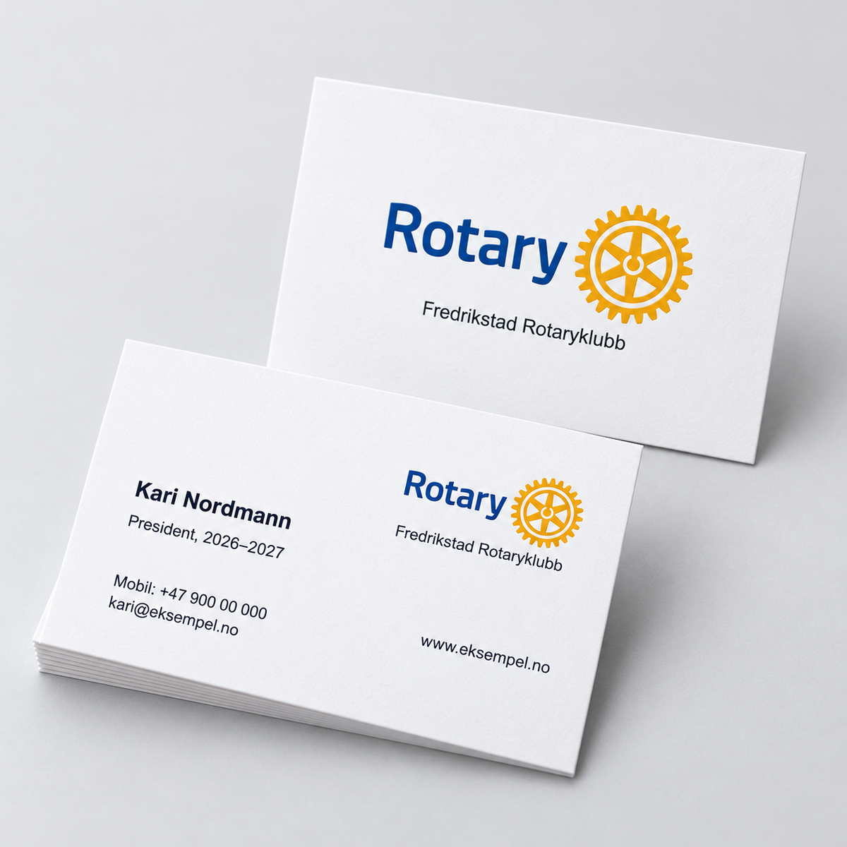 Rotary-visittkort vist i 3D med forside, bakside og Fredrikstad Rotaryklubb som eksempel.
